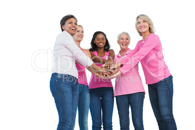 Women wearing breast cancer ribbons with hands together and smil