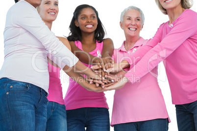 Happy women wearing breast cancer ribbons with hands together