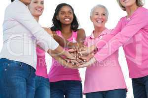 Happy women wearing breast cancer ribbons with hands together