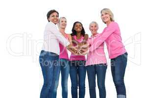 Cheerful women wearing breast cancer ribbons with hands together