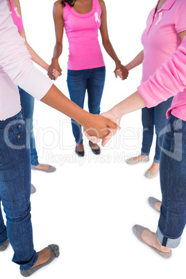 Women wearing pink and ribbons for breast cancer holding hands i