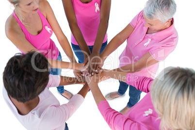 Group wearing pink and ribbons for breast cancer with hands toge