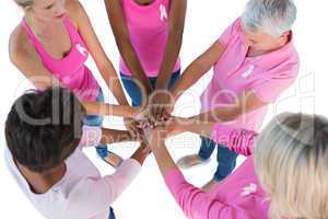 Group wearing pink and ribbons for breast cancer with hands toge