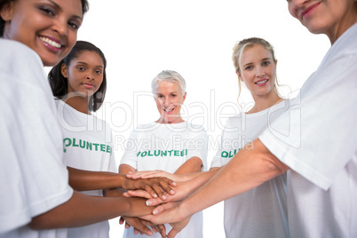 Team of female volunteers with hands together smiling at camera