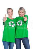 Two happy women wearing green recycling tshirts giving thumbs up