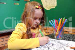 little girl draws the drawing at the table