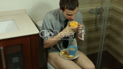 Crazy man eating on the toilet