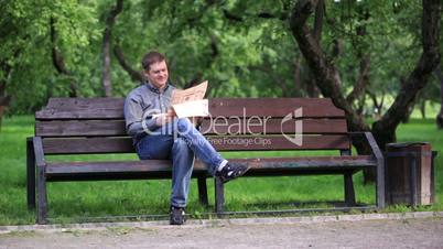 man reads newspaper on bench in the park 1