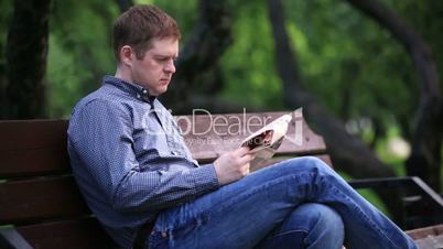man reads newspaper on bench in the park 2
