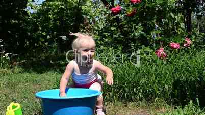 little girl playing in basin with water, summer day