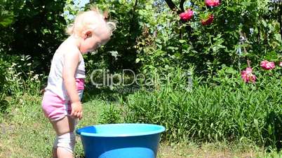 little girl playing in basin with water, summer day