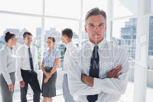 Boss with arms folded standing in a modern office