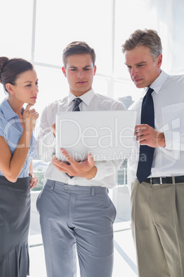 Three business people using a laptop