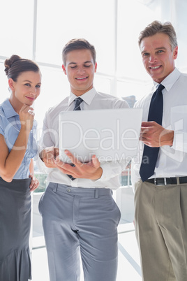 Three smiling business people using a laptop