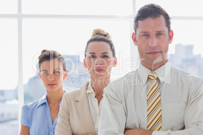 Serious handsome businessman standing with arms folded