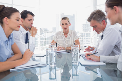 Businesswoman looking at camera with colleagues working around