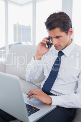 Businessman calling with his cell phone and using his laptop