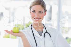 Attractive woman doctor showing an apple