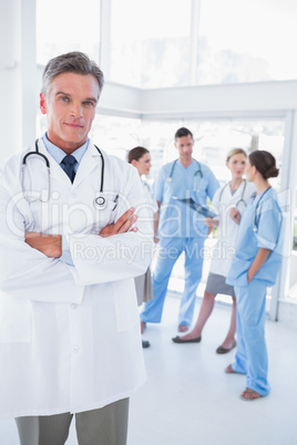Doctor with arms folded in front of his medical team