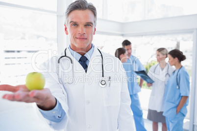 Doctor presenting an apple in his hand