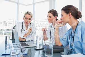 Three women doctors watching a laptop