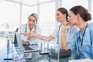Doctor showing something on a laptop to her colleagues