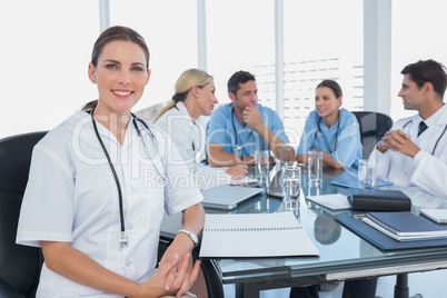 Smiling woman doctor looking at the camera in front of her team
