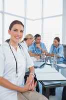 Attractive doctor sitting in front of her team