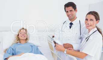 Smiling doctors standing next to a patient