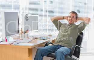 Smiling designer leaning back at his desk