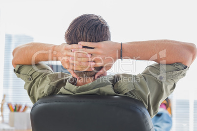 Rear view of a designer relaxing with foot on the desk