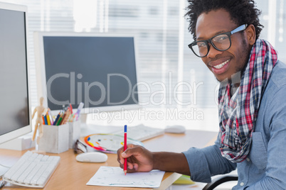 Smiling designer drawing something with a red pencil