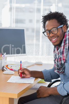 Cheerful designer drawing something with a red pencil