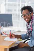 Cheerful designer drawing something with a red pencil