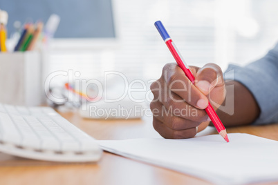 Man drawing with a red pencil on a desk
