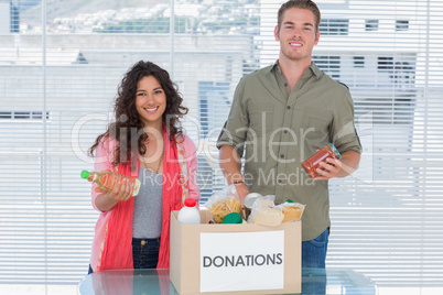 Smiling volunteers taking out food from donations box