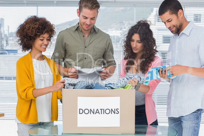 Happy team of volunteers taking out clothes from a donation box