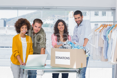 Volunteers using a laptop and taking clothes from a donation box