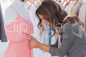 Fashion designer measuring dress on a mannequin