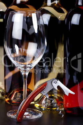Weinglas, Korkenzieher und Weinflaschen