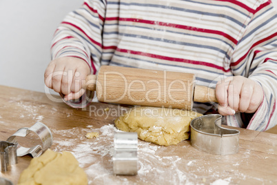 child rolling dough on wooden desk