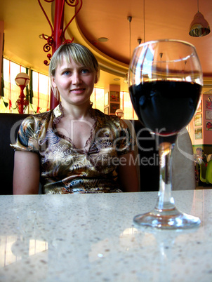 glass of red wine on the table and a girl