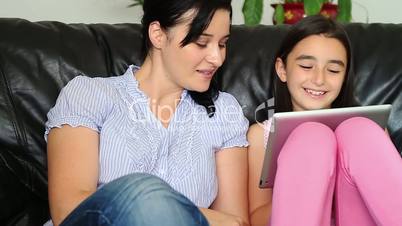 smiling mother and daughter using tablet computer