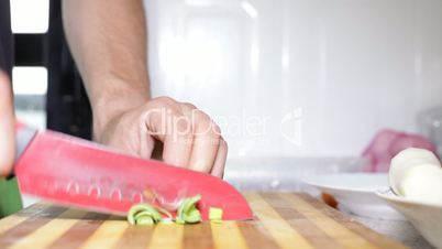 Hand with knife cutting fresh leek