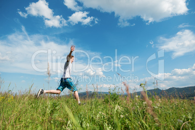 The boy jumps on a green grass