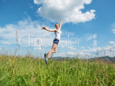 The girl jumps on a green grass