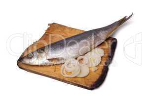 herring with onion rings on old wooden cutting board