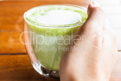 Hand on hot drink of matcha green tea latte
