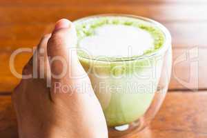 Hand on hot matcha green tea latte glass