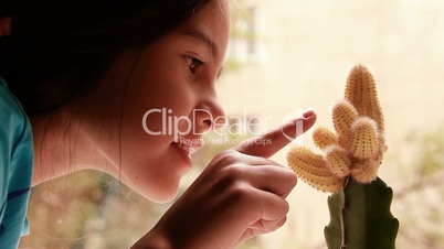 The girl touches a cactus.